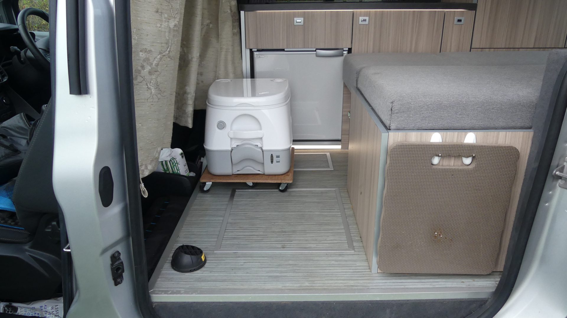 Dometic potty in front of fridge at end of bed